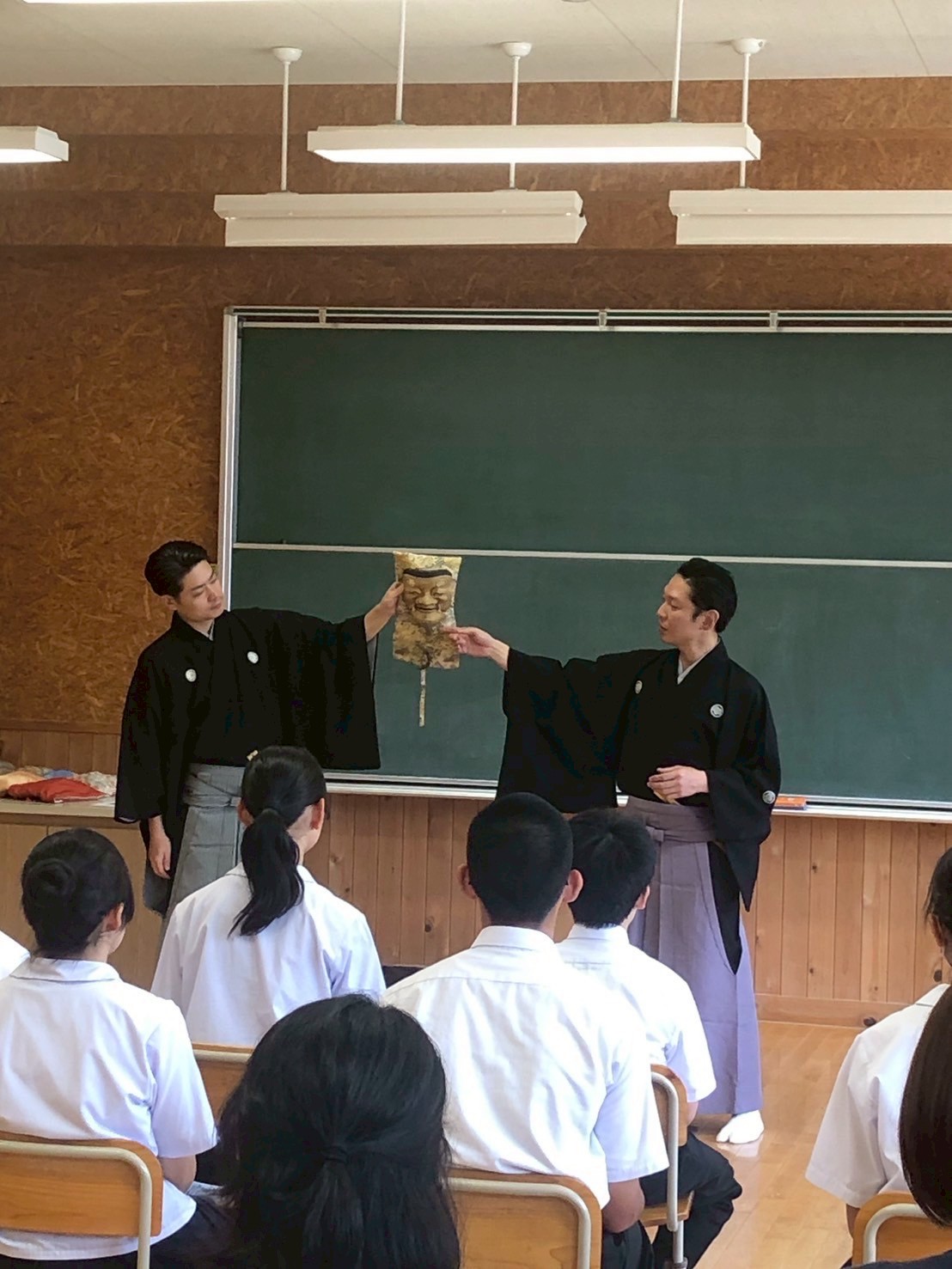 生徒たちの前で能面を紹介する能楽師